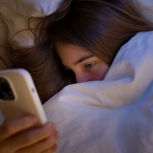 Adolescente usando o celular à noite, imersa no mundo digital e distante da privacidade.
